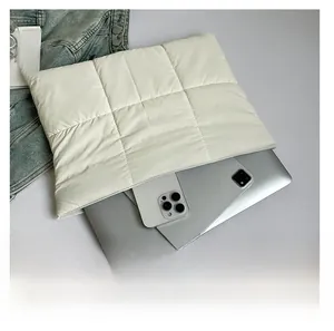 Capacity display of cream quilted laptop bag holding a notebook and a smartphone