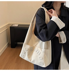 Vue détaillée du sac cabas en toile beige avec écussons lettrés 3D et longues bandoulières