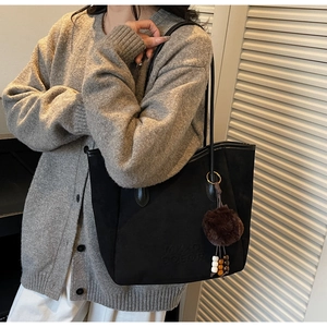 Détail du grand sac cabas en daim noir avec anses en cuir et pompon sur un modèle