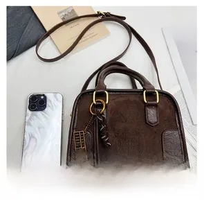 Détail du sac Boston en daim marron avec poignée anneau métal et bandoulière en chaîne