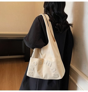 Détail d'un sac cabas en toile blanc cassé avec lettres nuosiman porté par un mannequin de côté