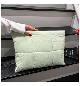 Detail of mint green quilted clutch bag featuring large square padding and soft texture