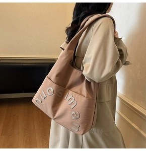 Détail du sac cabas vieux rose avec lettrage texturé porté par un mannequin en trench