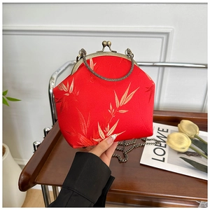 Detail of red satin handbag with golden bamboo embroidery and retro metal clasp