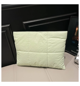 Close-up of a light green quilted handbag with waterproof nylon fabric and grid texture