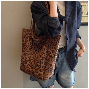 Detailed close-up of a large leopard print tote bag with soft suede texture on a model