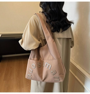 Détail d'un grand cabas en toile rose poudré avec large bandoulière et broderie lettrée