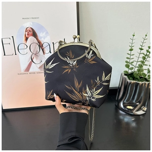 Detail of elegant black shell bag with bamboo leaf embroidery and metal chain strap