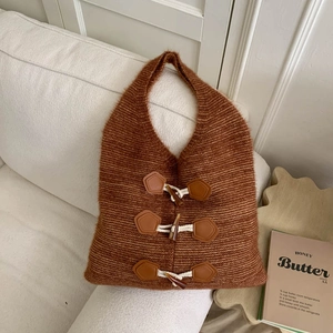 Close-up of knit hobo bag with leather toggle buttons on a cozy fabric sofa