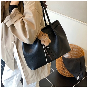 Detail view of large black PU leather tote bag with a cute brown plush bear charm
