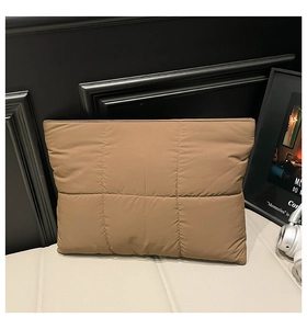 Detailed view of brown quilted padded clutch showing the puffed nylon fabric and square stitching