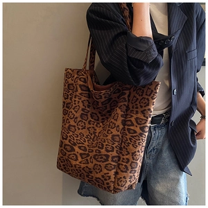 Detail shot of a large leopard print tote bag with soft texture on a female model shoulder