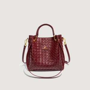 Dettaglio borsa a secchiello in pelle intrecciata bordeaux con finiture metalliche dorate
