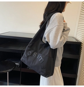 Détail du grand sac cabas noir en nylon avec lettres nuosiman porté par un mannequin de côté