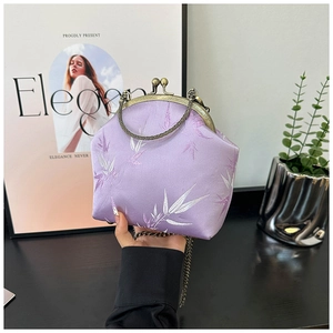 Detail of lavender satin bag featuring silver bamboo leaf patterns and retro bronze clasp