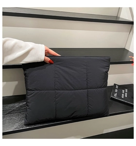 Detail of a black quilted puffer clutch bag showing premium nylon texture and square pattern