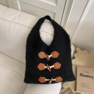 Close-up of black knit tote bag featuring three brown leather toggle button closures