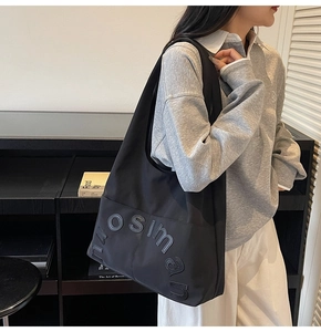 Détail du lettrage en relief 3D sur un sac fourre-tout noir en toile pour femmes