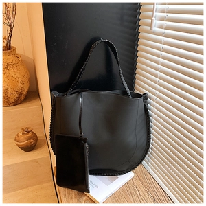 Detail of matte black tote bag showing woven handles and matching zippered pouch