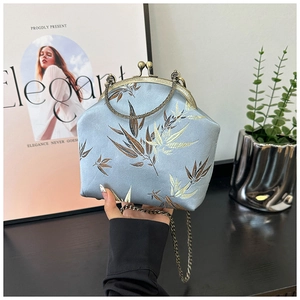 Close-up of light blue silk bag with bamboo embroidery and vintage metal chain strap