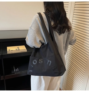 Détail d'un grand sac fourre-tout en toile noire avec broderie porté à l'épaule