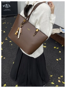 Brown leather tote bag with colorful bead tassel detail worn by model outdoors