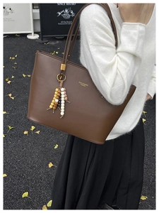 Detail of dark brown leather tote bag with FDJY logo and wood bead tassel charm