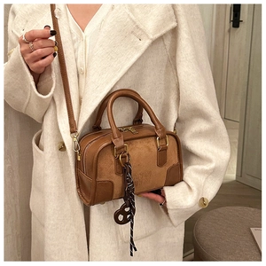 Détail de la couture en cuir marron et daim du sac Boston avec logo embossé