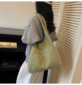 Détail du sac fourre-tout en toile vert sauge avec logo nuosiman en relief et attaches métal
