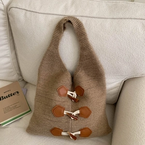 Detail of khaki knit tote bag featuring retro horn buckle accents and soft texture
