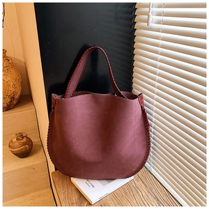 Close-up of wine red suede tote bag with intricate hand-woven edges and vintage texture