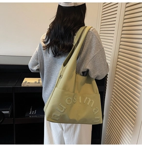 Détail d'un grand cabas en toile vert avocat avec lettrage en relief sur la poche avant