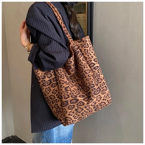 Side view of large leopard print tote bag with soft suede texture on a female model