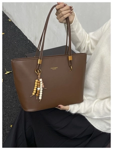 Detail of coffee brown tote bag with colorful wooden bead tassel and gold logo