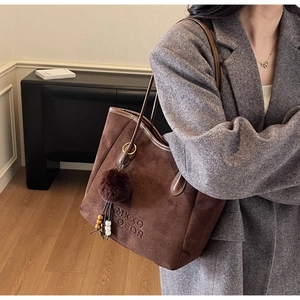 Détail du sac cabas en daim marron foncé avec gaufrage et breloque en fourrure douce