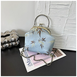 Detail of vintage blue silk shell bag with bamboo patterns and ornate metal handle
