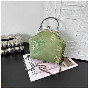 Detailed embroidery of green bamboo leaves on vintage satin bag with bronze frame