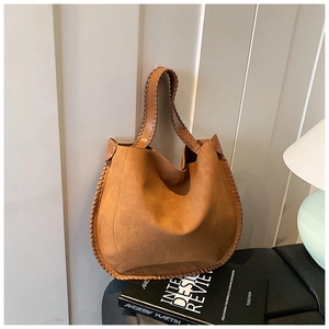 Close-up of brown suede tote bag with intricate woven edge detailing and soft hobo texture
