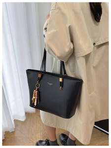 Detailed back view of a black leather tote bag featuring colorful bead charms and gold hardware