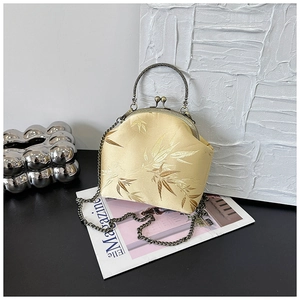 Close-up of yellow silk bag with bamboo pattern, antique bronze handle and chain strap