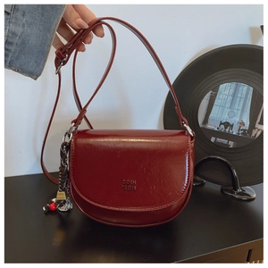 Détail du sac à main bordeaux montrant la texture du cuir brillant et le logo gaufré
