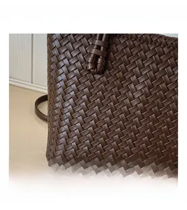 Gros plan sur la texture en cuir tressé marron foncé et les détails de ce sac seau chic