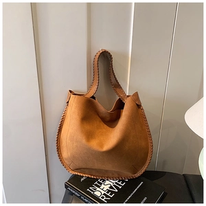 Detail showing high-quality brown suede texture with handmade whipstitch edges on the tote bag