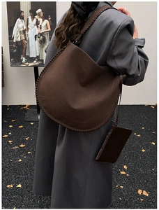 Detail of dark brown leather hobo bag with whipstitch edges and matching small pouch
