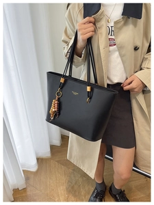 Detail of black matte PU leather tote bag with gold metal hardware and beaded charm