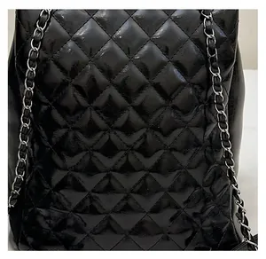 Detail of black quilted leather backpack with silver chain and vintage stitching