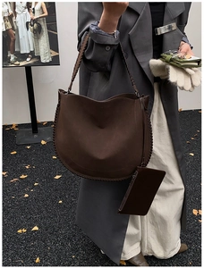 Detail of a large brown tote with woven edges and a matching zippered pouch in a street scene