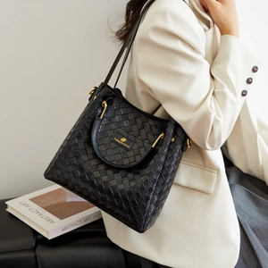 Dettaglio borsa a secchiello in pelle intrecciata nera con logo dorato e tracolla