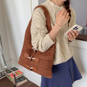 Detail of chunky knit shoulder bag with brown leather base and toggle buttons on strap