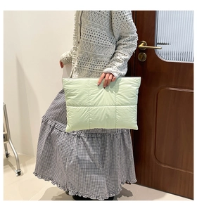 Detail of mint green quilted puffer laptop sleeve featuring soft fabric texture and zipper